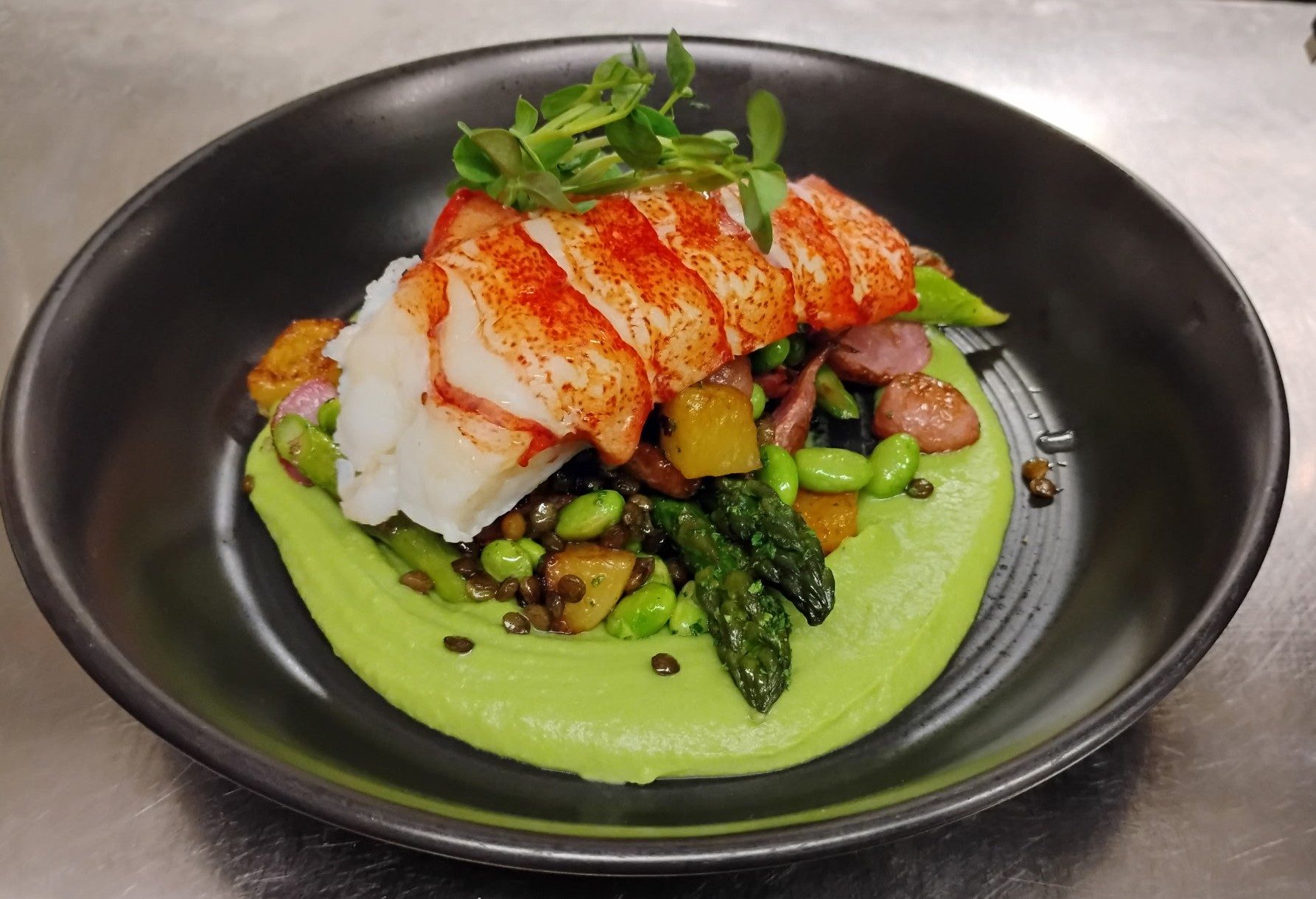 Butter poached lobster tail on green pea purée with asparagus, edamame and lentils